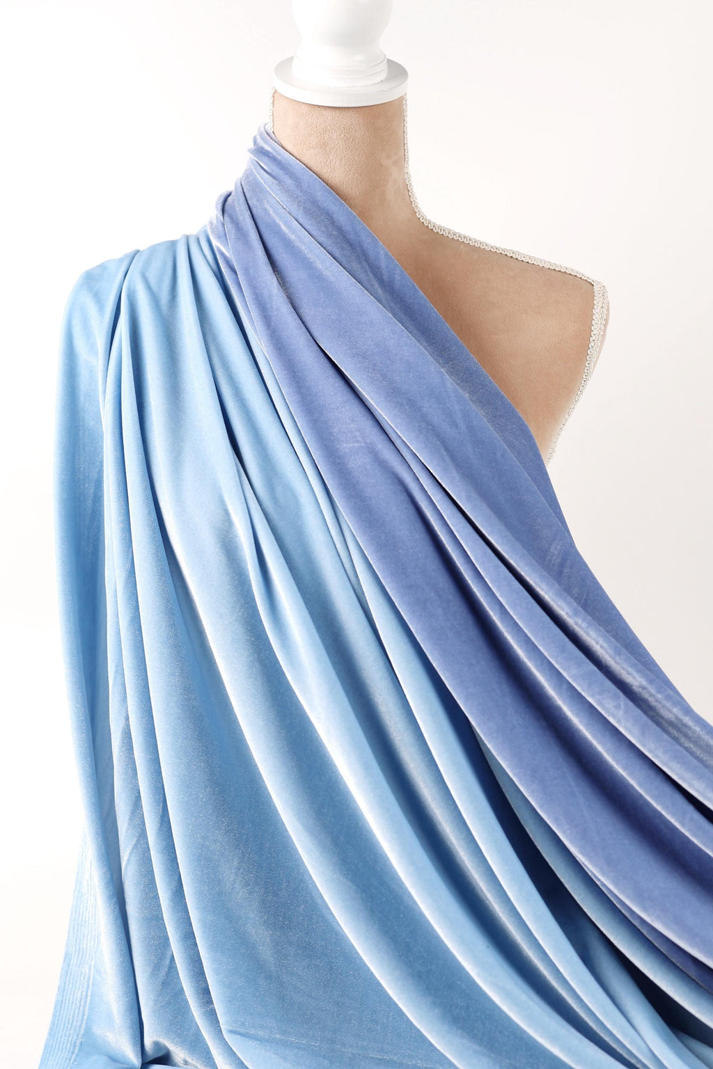 A mannequin wearing a blue and white draped fabric draped over its body.