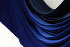 a close-up view of a blue fabric with a shiny, glittery texture. The fabric appears to be made of a shiny, metallic material, giving it a luxurious and elegant appearance.