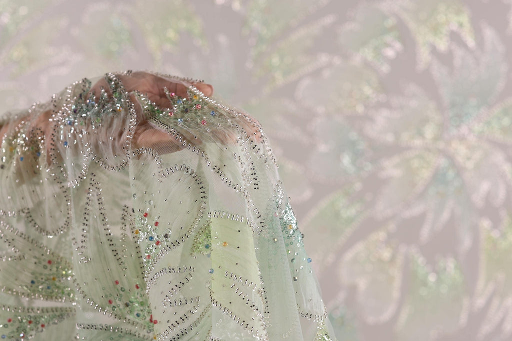 A close-up view of a delicate, intricately embroidered fabric with a floral pattern.