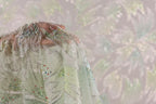 A close-up view of a delicate, intricately embroidered fabric with a floral pattern.