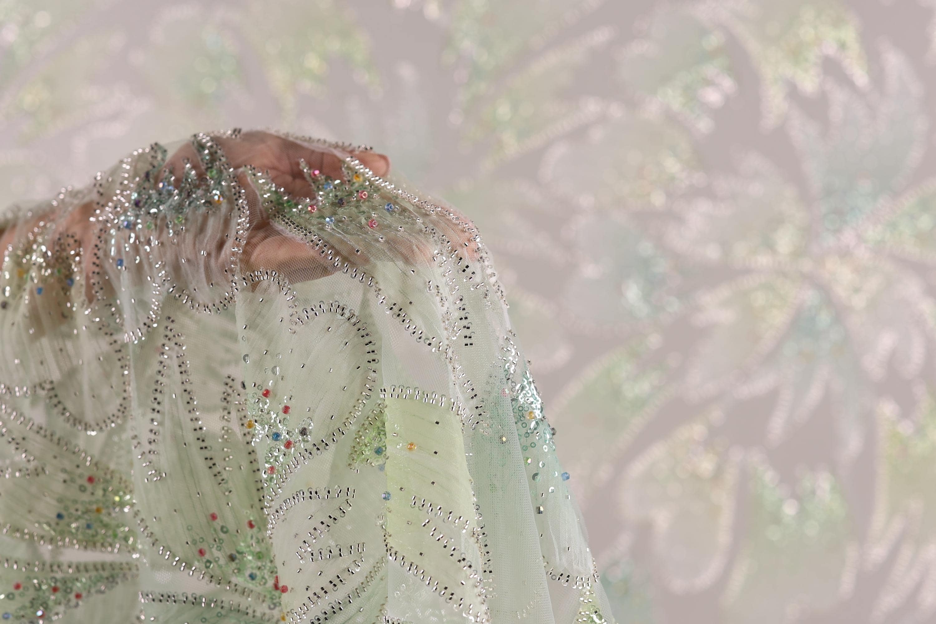 A close-up view of a delicate, intricately embroidered fabric with a floral pattern.