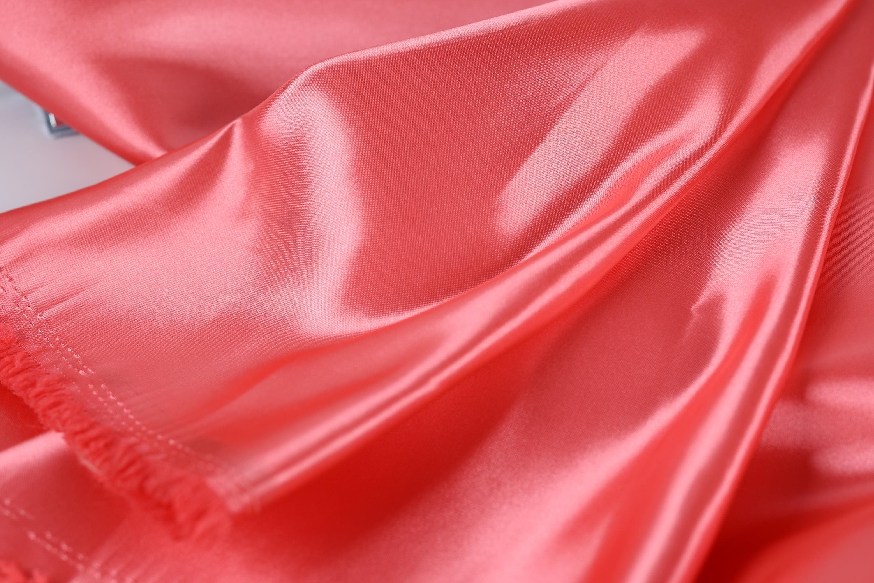 A close-up view of a shiny, smooth fabric in a bright red color.