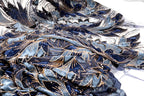 a close-up view of a fabric with a blue and gold floral pattern. The fabric appears to be made of a shiny material, possibly sequin or lace, and has a textured, crumpled appearance.