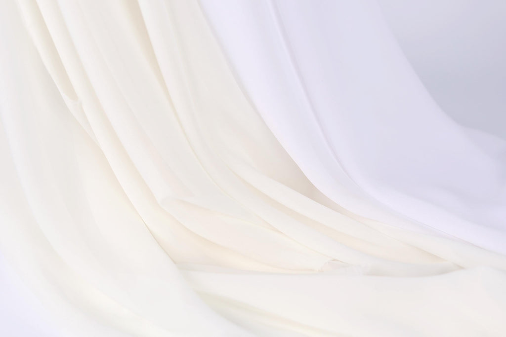 The image is a close-up of a white fabric, possibly a sheer or sheer-like material, with a soft, flowing texture. The fabric appears to be draped or folded in a way that creates a sense of movement and softness.