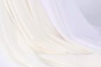The image is a close-up of a white fabric, possibly a sheer or sheer-like material, with a soft, flowing texture. The fabric appears to be draped or folded in a way that creates a sense of movement and softness.