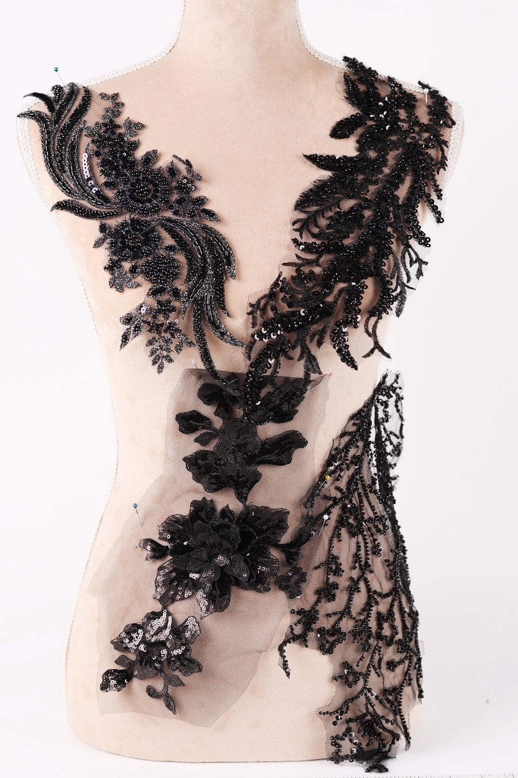 A mannequin wearing a dress with intricate black lace and floral embellishments.