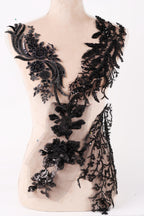 A mannequin wearing a dress with intricate black lace and floral embellishments.