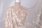 A mannequin wearing a white lace dress with a sheer, flowing fabric draped over it.