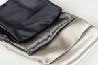 a close-up view of three different colored satin fabrics, including black, gray, and white, arranged in a layered fashion.