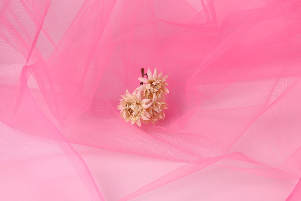 A single light pink flower is the focal point of the image, set against a soft pink background.