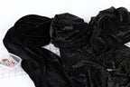 a close-up view of a black fabric with glittery or sparkly elements, possibly a piece of clothing or a decorative material. There is a small container of pins or sewing tools placed next to the fabric.