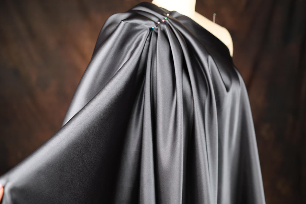 a woman wearing a black cape with a flower on it