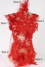 A mannequin wearing a red dress with intricate red lace details, including floral and leaf patterns.