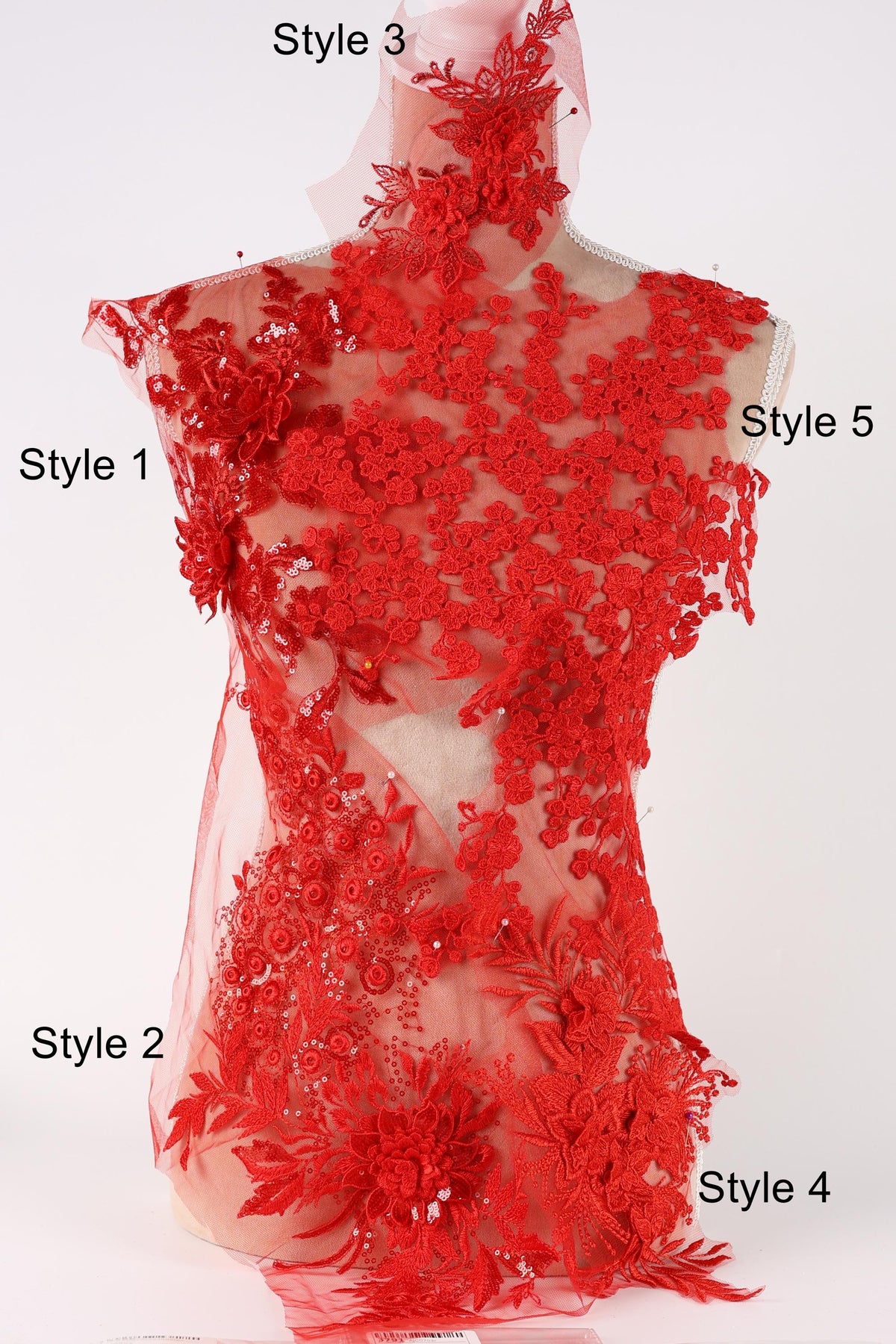 A mannequin wearing a red dress with intricate red lace details, including floral and leaf patterns.