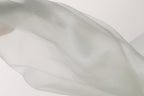 The image is a close-up of a white fabric, possibly a sheer or sheer-like material, with a soft, flowing texture.