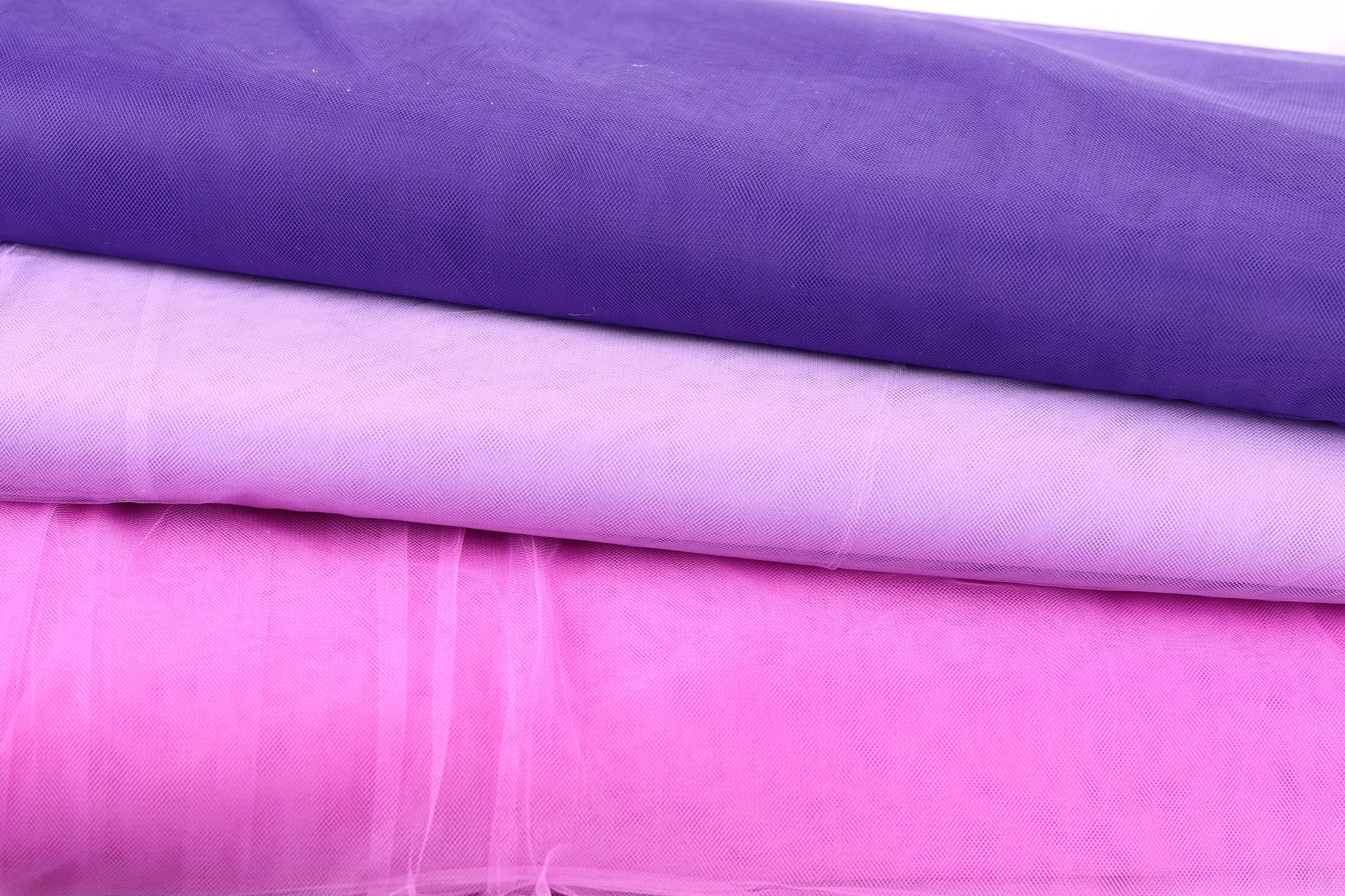 a close-up view of three fabric swatches in different colors: purple, pink, and white.