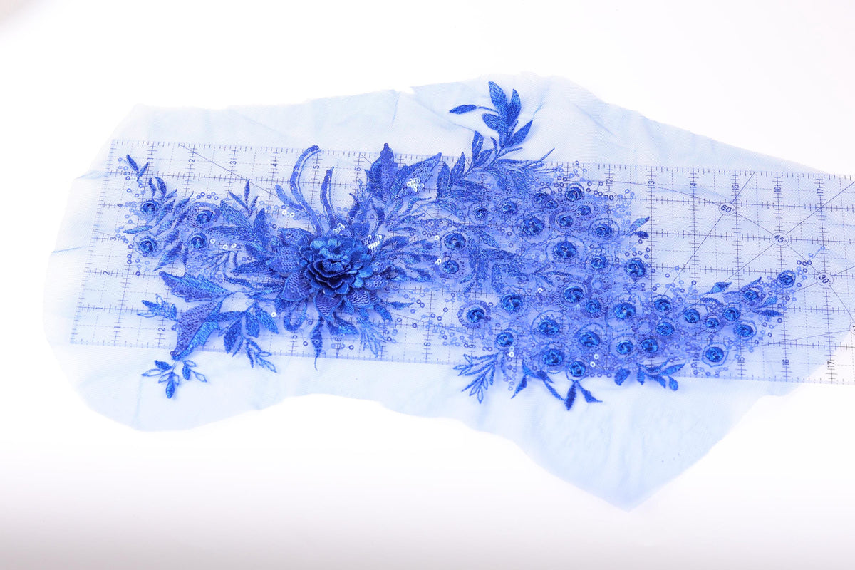 a close-up view of a blue floral embroidery design on a piece of fabric, with a ruler visible in the background.