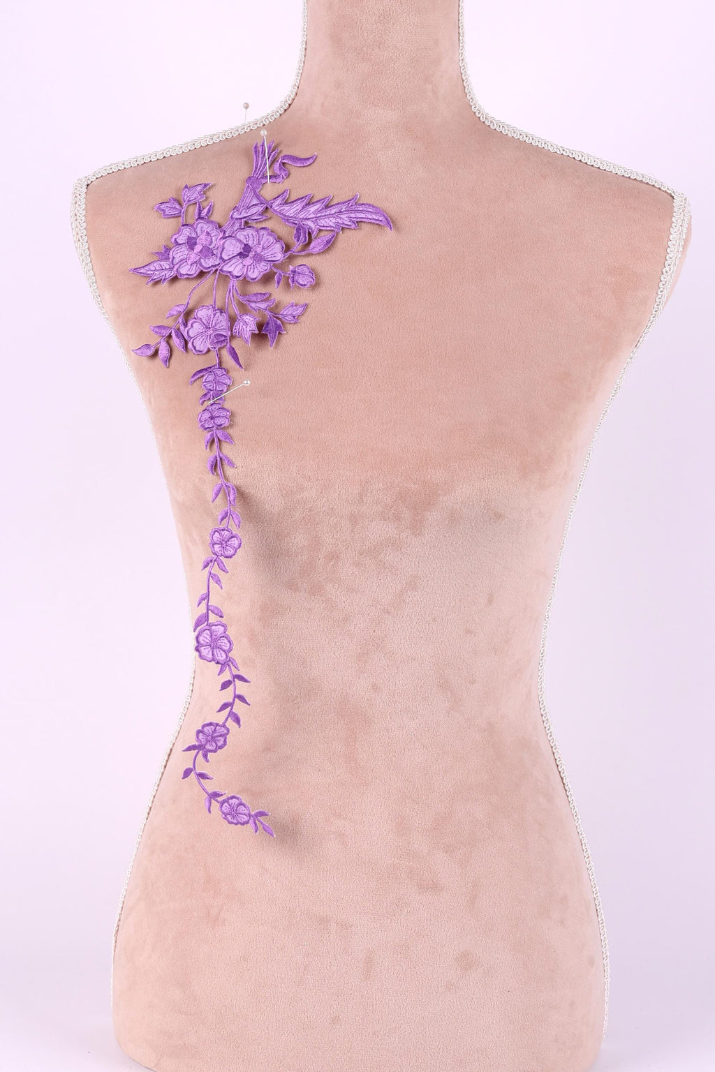 a mannequin with a decorative purple embroidered flower on its shoulder.