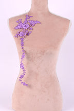 a mannequin with a decorative purple embroidered flower on its shoulder.
