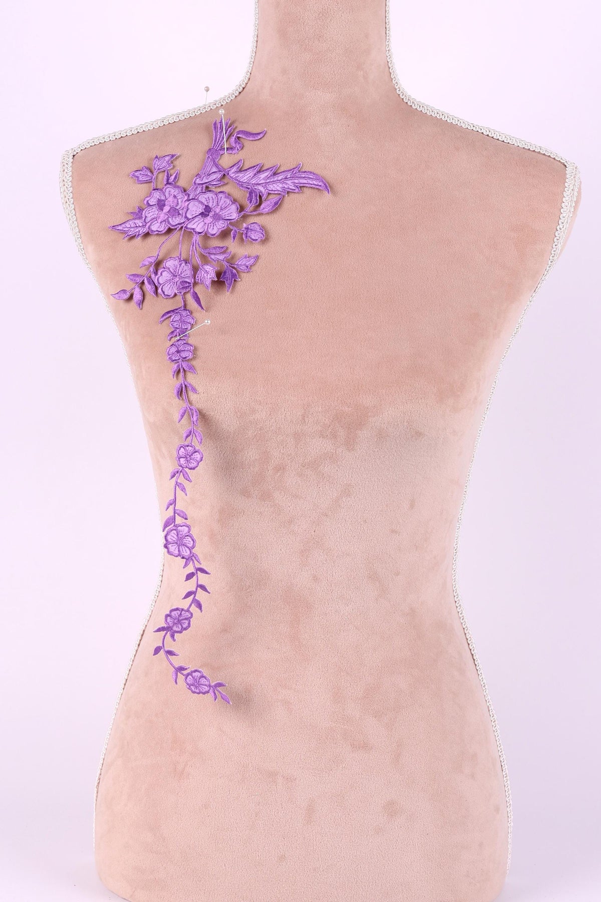 a mannequin with a decorative purple embroidered flower on its shoulder.