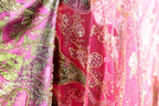 a close-up view of a fabric with a pink and green floral pattern, featuring sequins and beads.