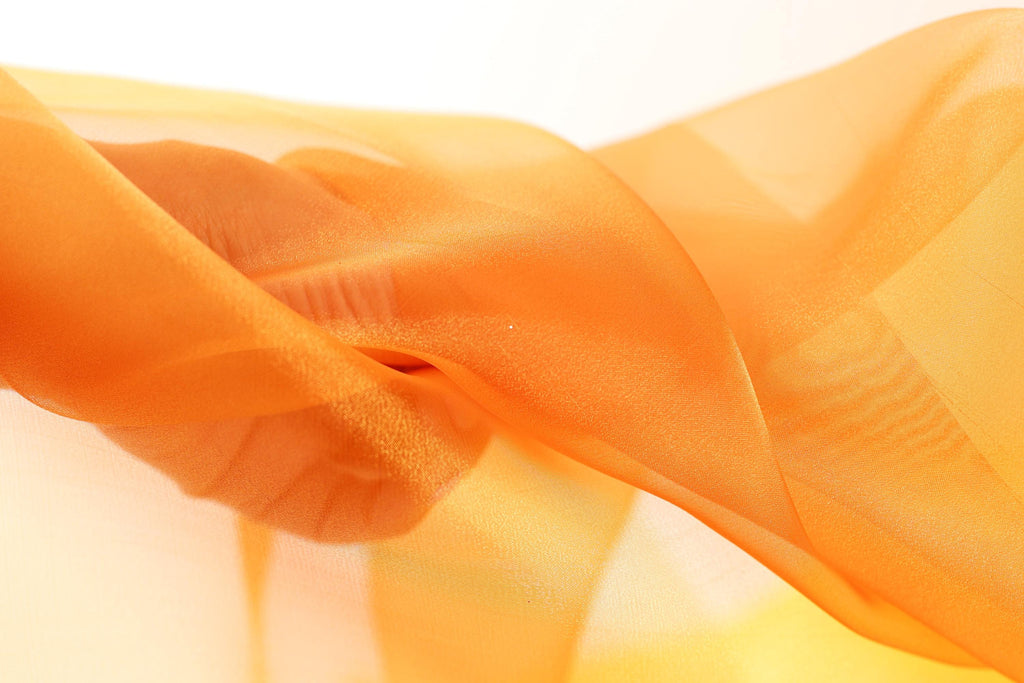 The image is a close-up of a fabric with a soft, flowing texture in shades of orange and yellow.