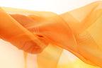 The image is a close-up of a fabric with a soft, flowing texture in shades of orange and yellow.