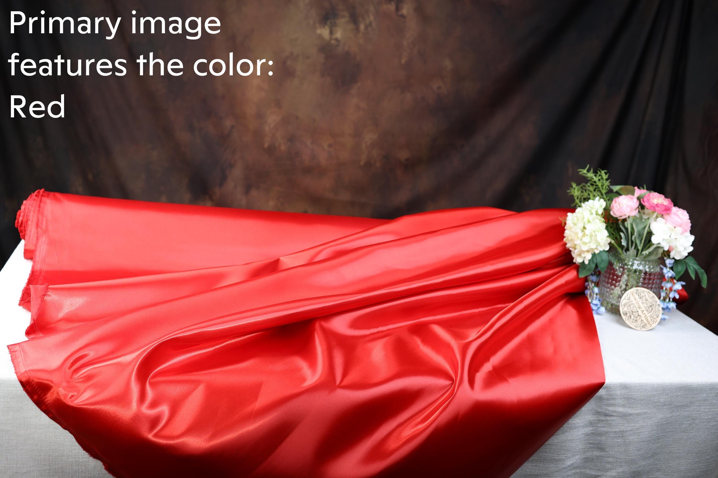 a red fabric, a vase with flowers, and a dark background.