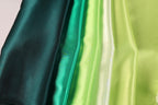 A close-up image of a collection of fabric swatches in various shades of green, including dark green, lime green, and mint green.