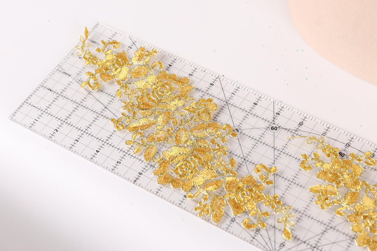 a clear ruler with a gold floral pattern on it, placed on a white surface.