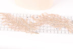 a close-up view of a delicate, beige-colored lace or fabric with a ruler placed on top of it, indicating it is being measured or cut.