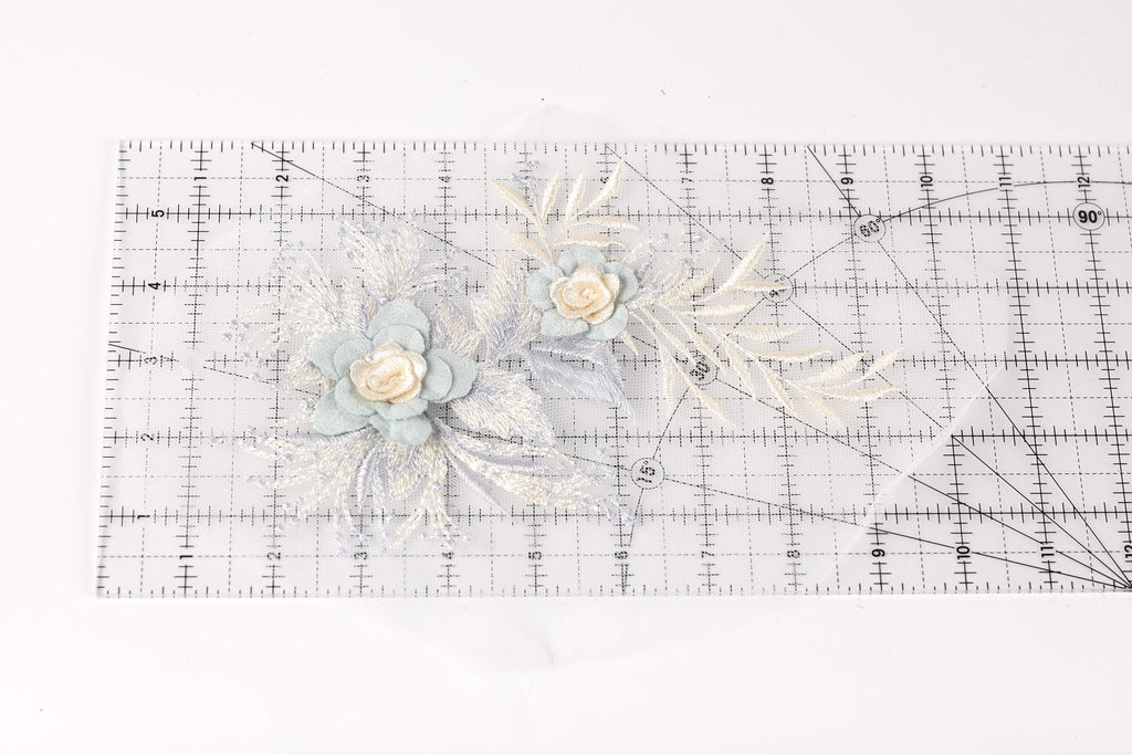 a clear ruler with a floral design on it, including two blue flowers and some white leaves.