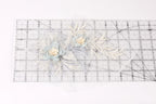 a clear ruler with a floral design on it, including two blue flowers and some white leaves.