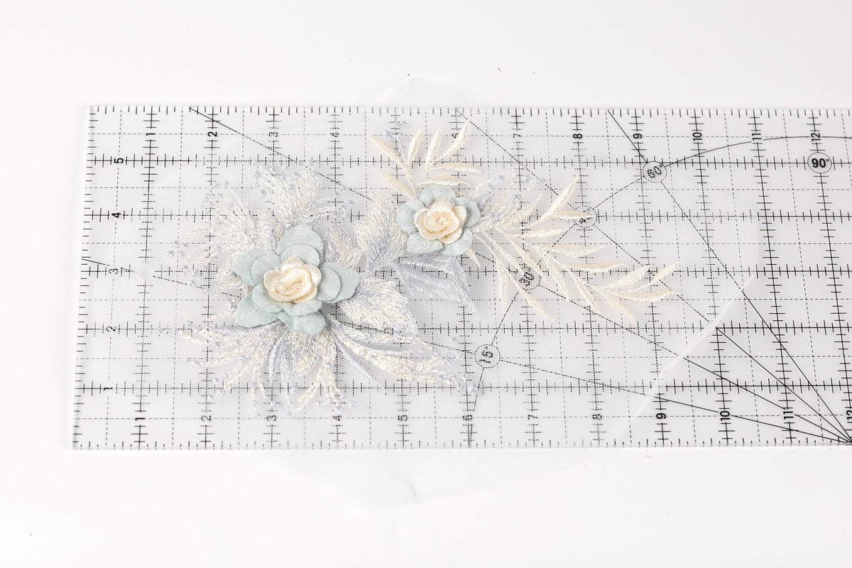 a clear ruler with a floral design on it, including two blue flowers and some white leaves.