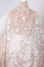 A close-up view of a delicate, lace-like fabric with a floral pattern.