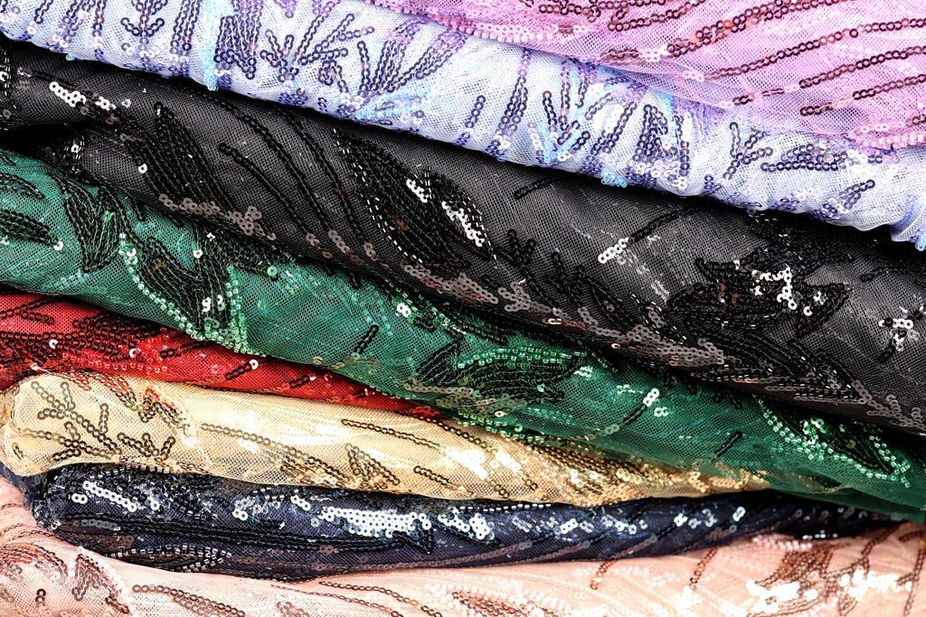 A close-up image of various colorful fabric pieces, including sequinned and sequined materials, stacked on top of each other.