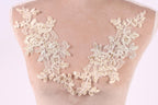 a close-up view of a delicate, intricate lace design on a mannequin or dress form. The lace features a floral pattern with leaves and flowers, creating a beautiful and elegant appearance.