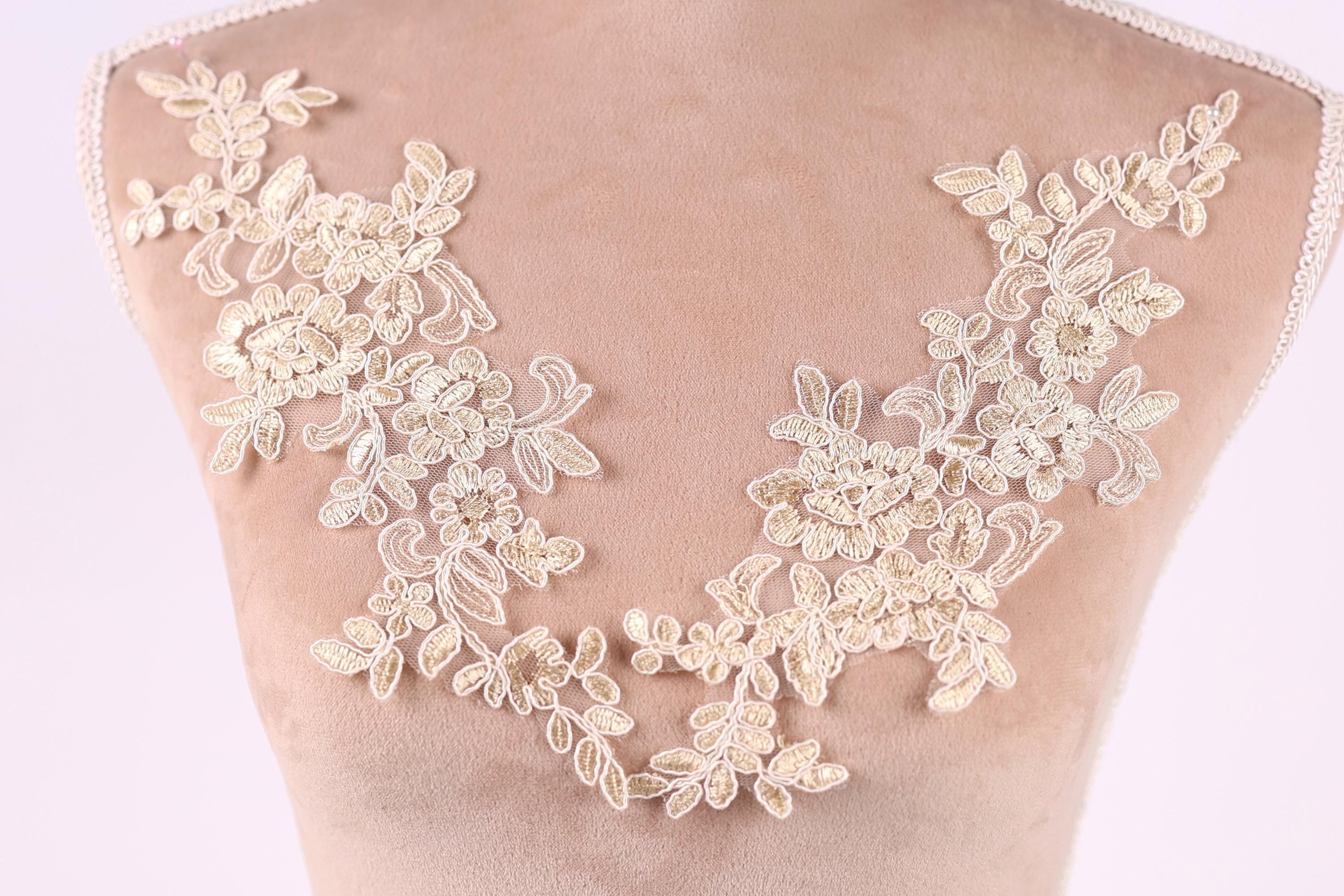 a close-up view of a delicate, intricate lace design on a mannequin or dress form. The lace features a floral pattern with leaves and flowers, creating a beautiful and elegant appearance.