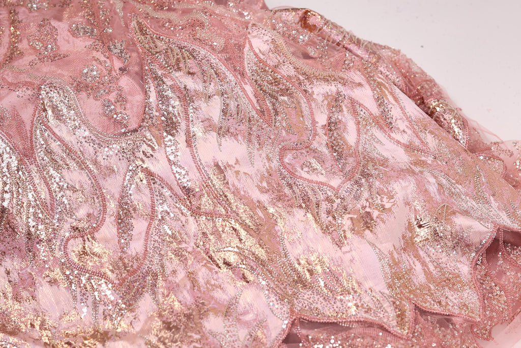 a close-up view of a pink and gold sequined fabric, with intricate patterns and designs.