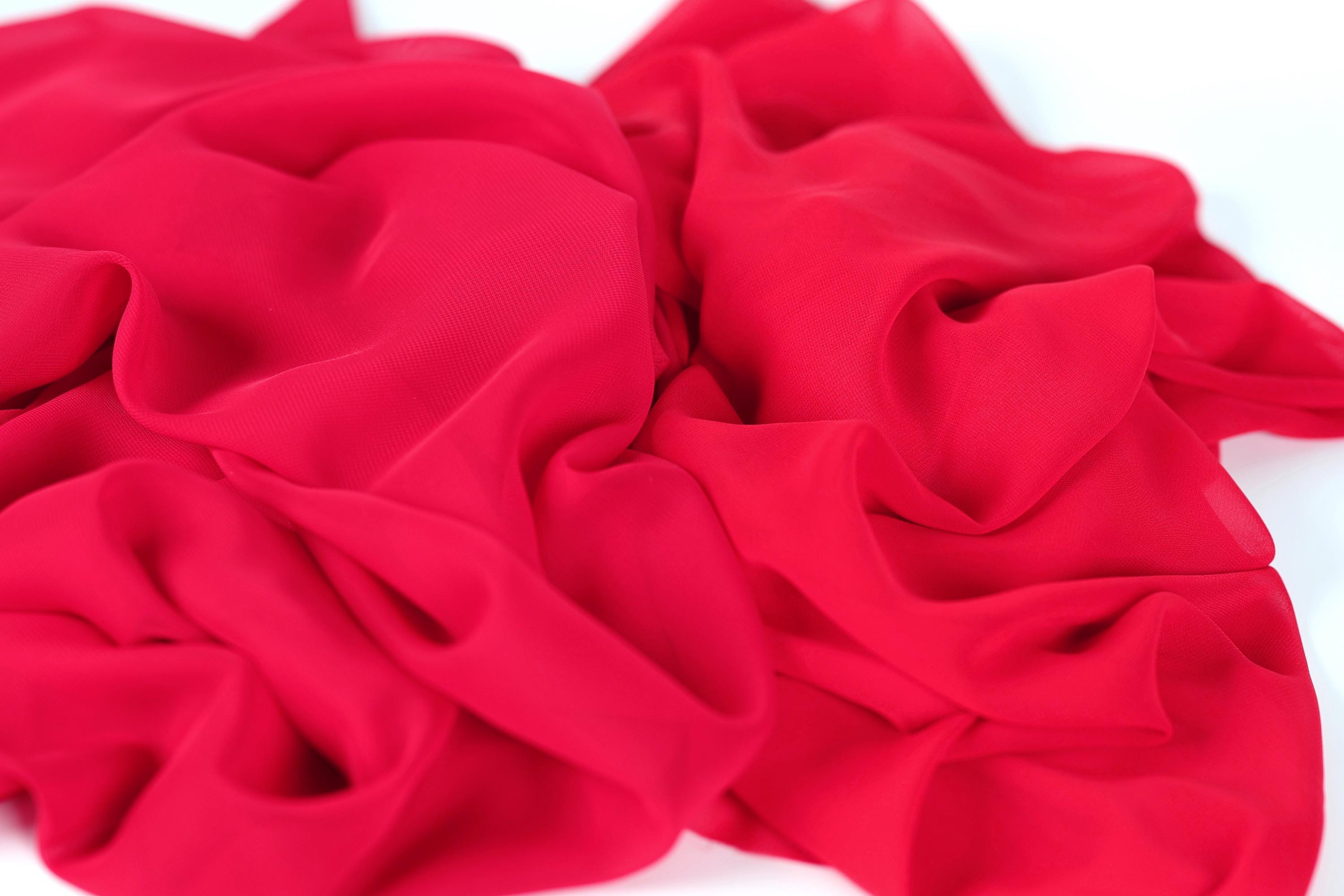 a close-up view of a red fabric, possibly silk or chiffon, with a crumpled and wrinkled texture.
