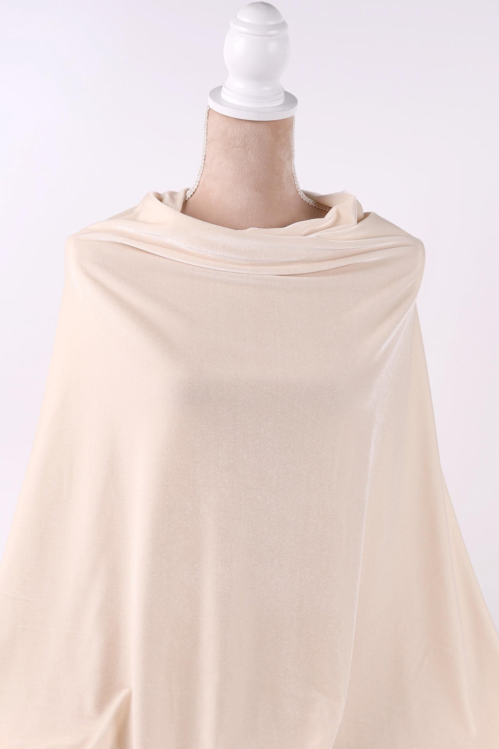 A mannequin wearing a cream-colored fabric draped over its body.