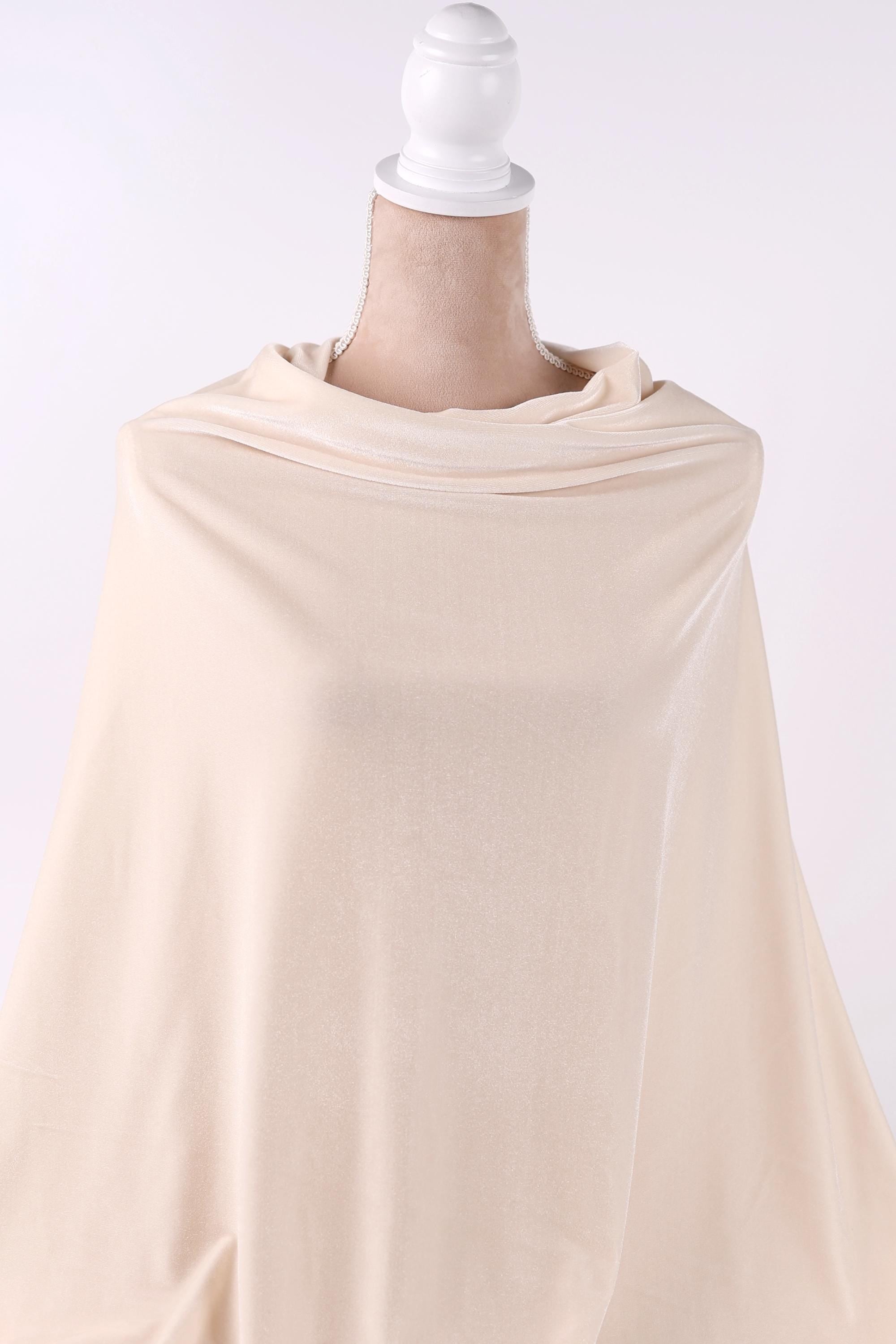 A mannequin wearing a cream-colored fabric draped over its body.