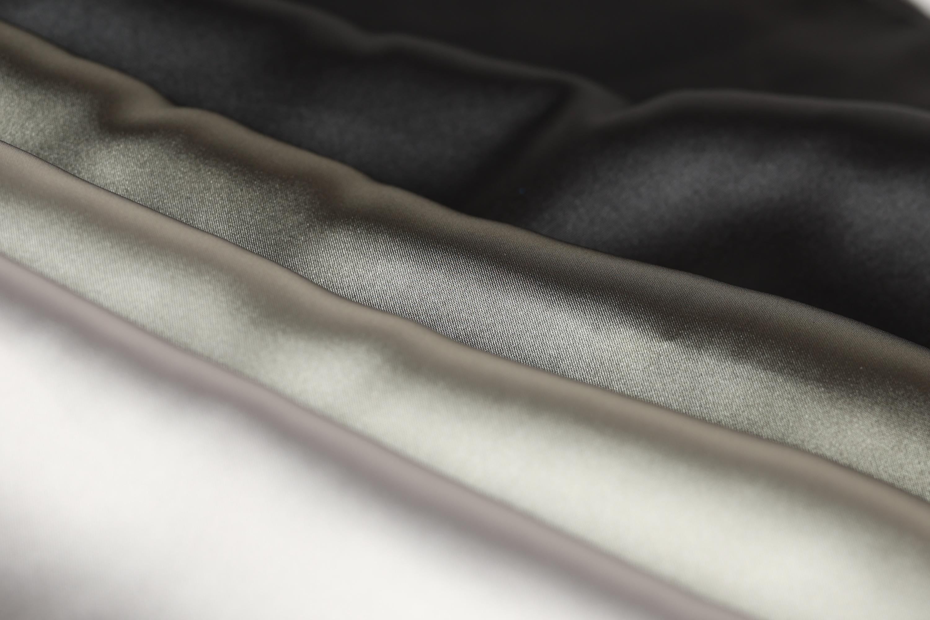 A close-up image of a fabric with a textured surface, featuring a range of colors from black to gray to white.