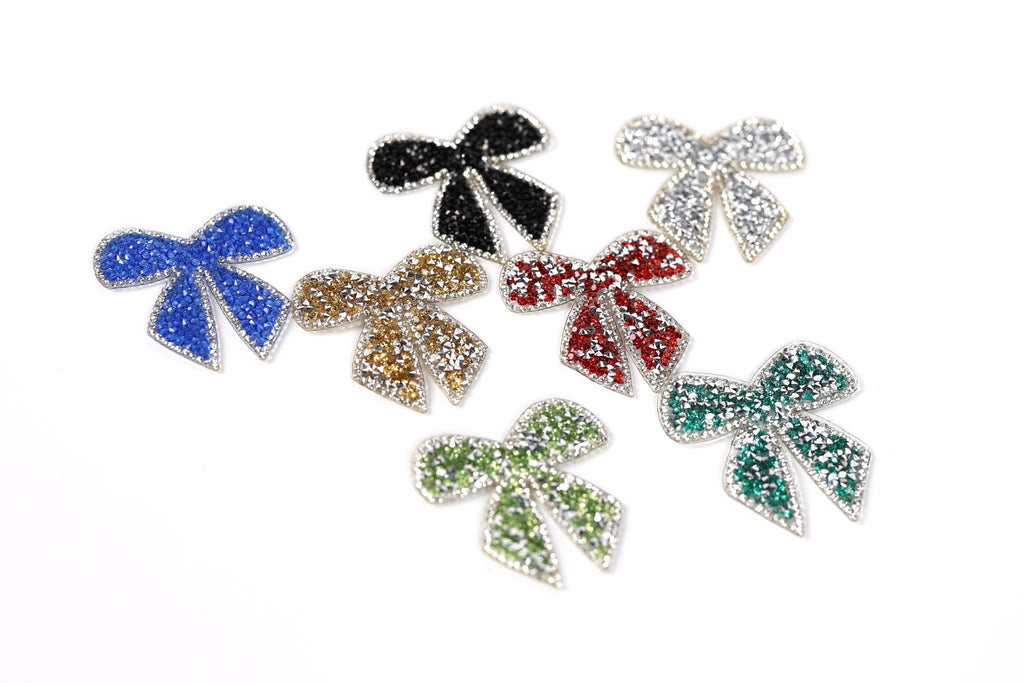 six colorful, glittery bows in various colors and sizes, arranged on a white background.