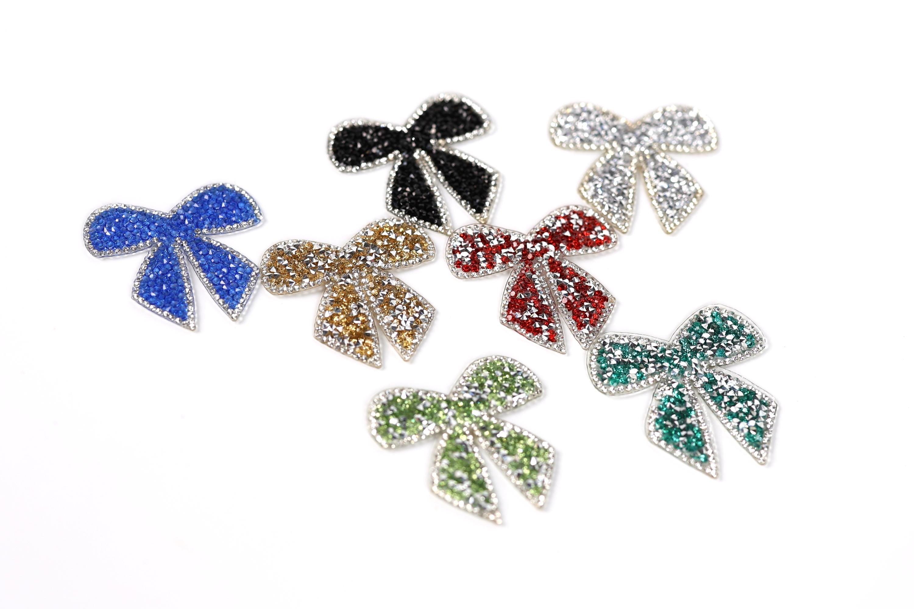 six colorful, glittery bows in various colors and sizes, arranged on a white background.