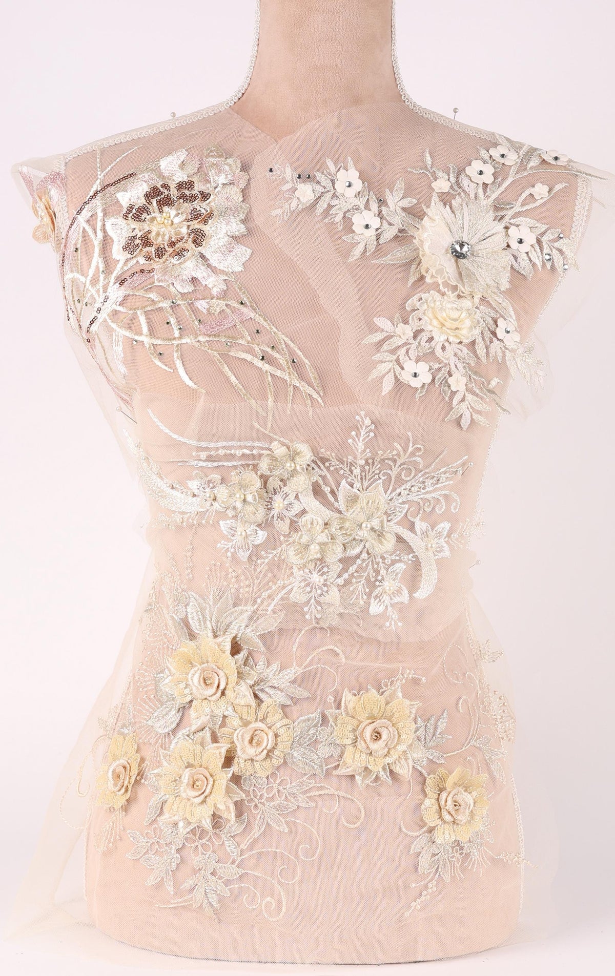 A mannequin wearing a white dress with intricate floral embroidery and lace details.