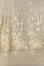 a close-up view of a delicate, shimmering fabric with a floral pattern. The fabric appears to be made of sequin material, giving it a sparkling and luxurious appearance. The floral design is intricate and detailed, with each flower and leaf meticulously crafted to create a visually appealing and elegant effect.