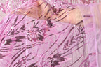 A close-up view of a hand holding a piece of pink and black sequin fabric.