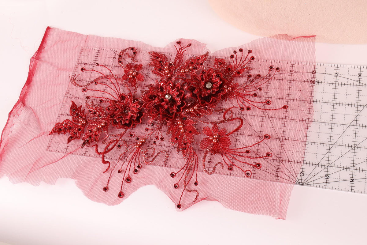 a close-up view of a red floral embellishment, possibly a piece of fabric or a decorative element, with a ruler placed on top of it.