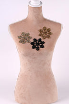 A mannequin with three different colored snowflake-shaped embellishments on its chest.